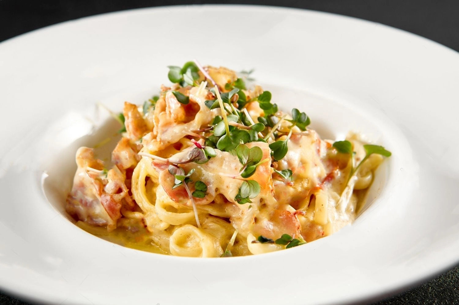 Assiette de pâtes carbonara fraîches garnies de micro-pousses Van Leaf, recette saine riche en nutriments pour un repas équilibré.